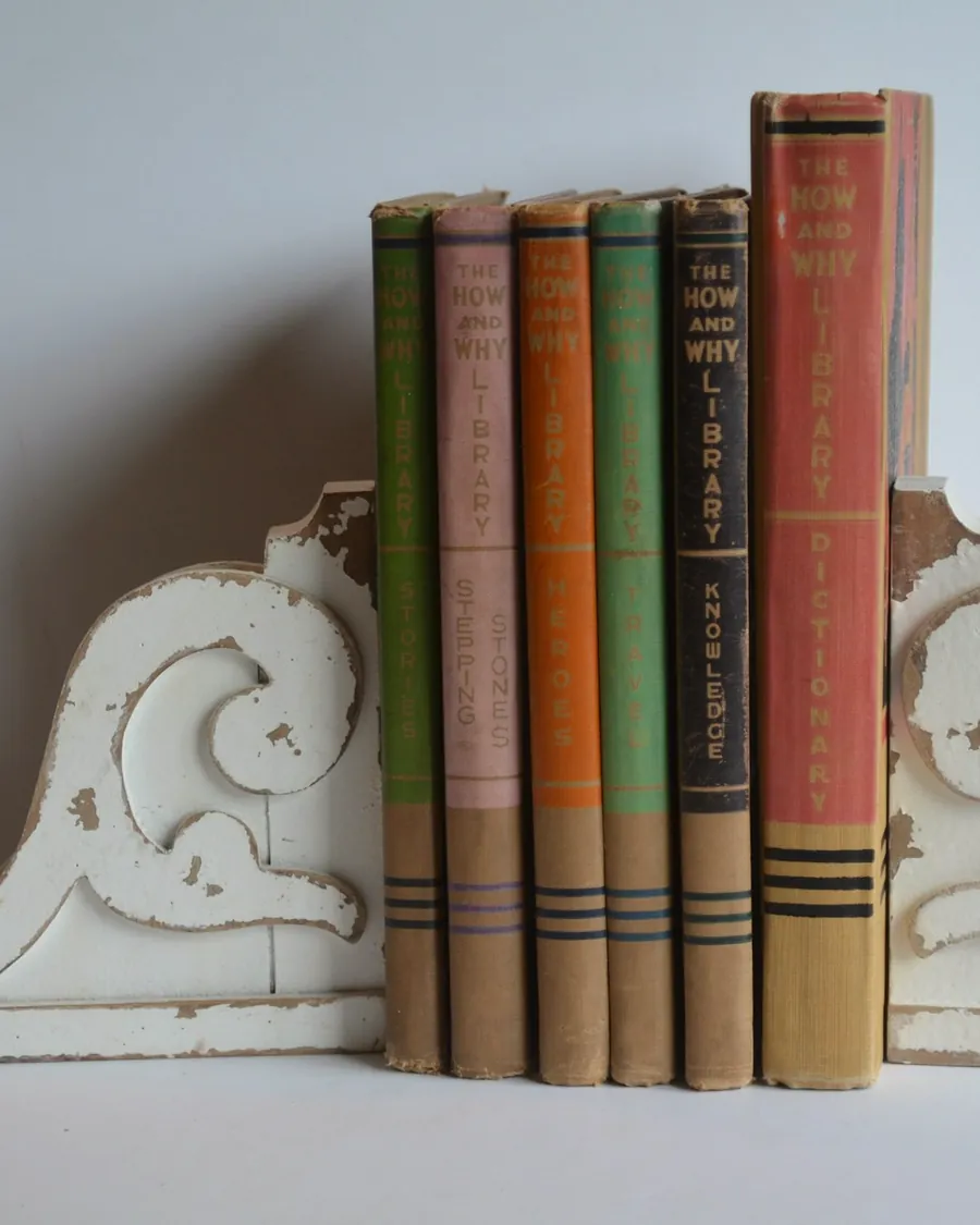Une rangée de livres anciens maintenus par deux serre-livres blancs sculptés