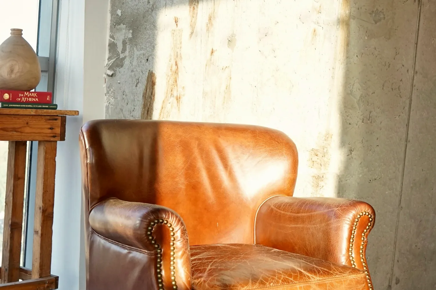 Un fauteuil en cuir orangé près d'une fenêtre baignée de lumière