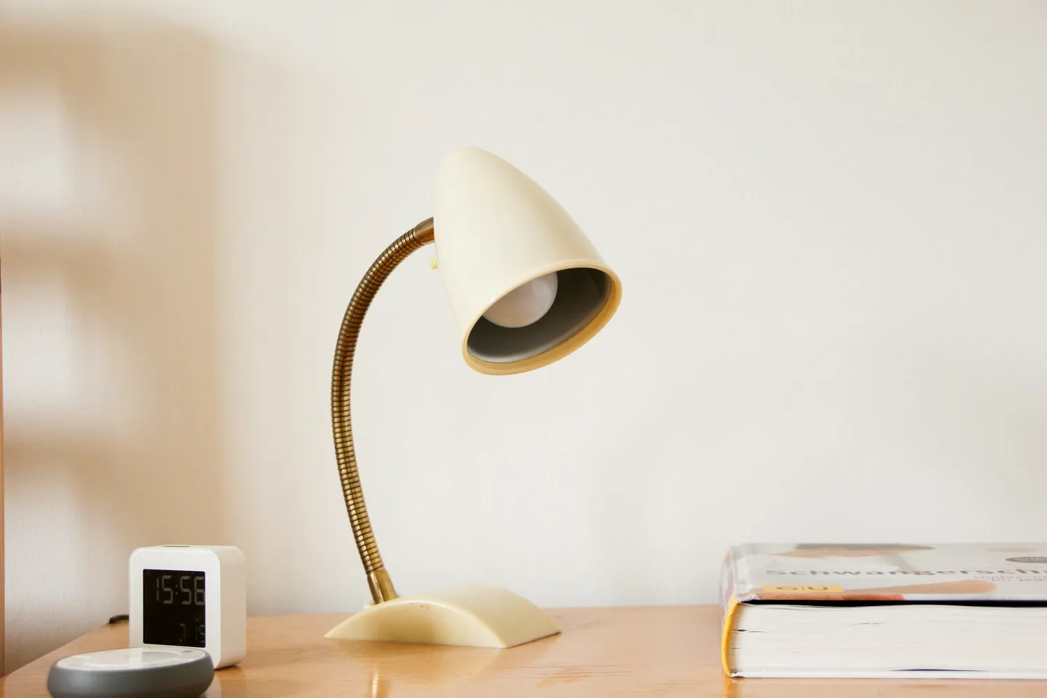 Une lampe de bureau allumée près de livres empilés sur une table