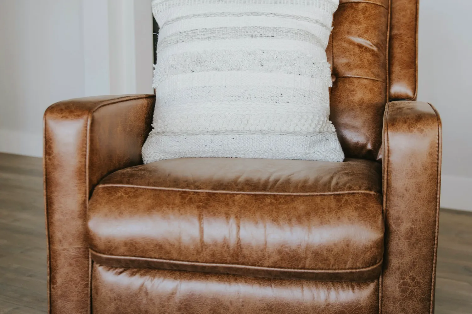 Un fauteuil en cuir brun garni d'un coussin clair