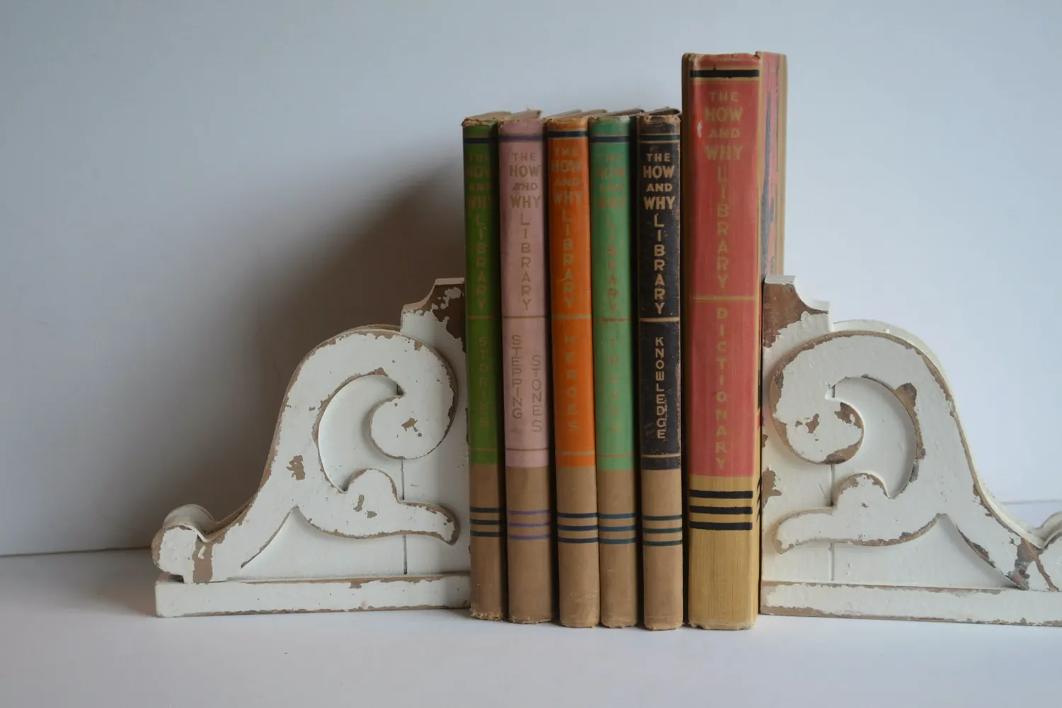 Une rangée de livres anciens retenue par deux serre-livres blancs sculptés
